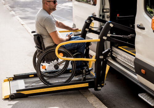 A man in a wheelchair on a lift of a vehicle for people with disabilities