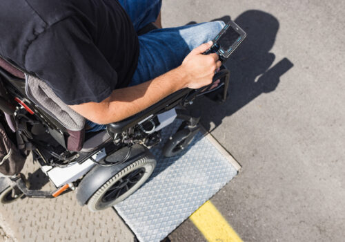 Male tourist on wheelchair crossing over the threshold ramp on the seaside promenade. Disability and accessible tourism concepts.