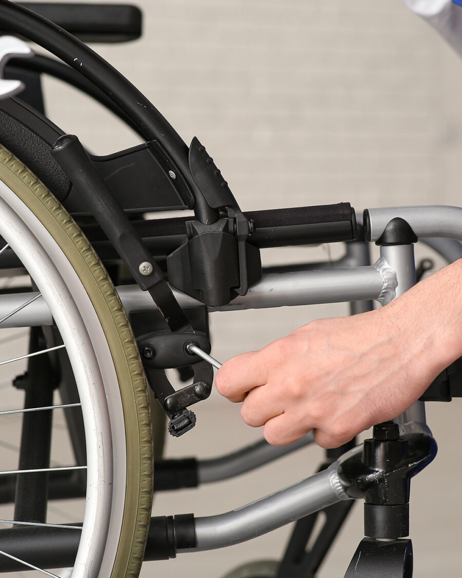 Male worker repairing wheelchair in room, closeup